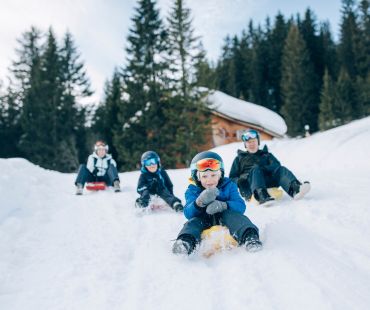 Kids enjoying sledding down the snowy trails Kids enjoying sledding down the snowy trails